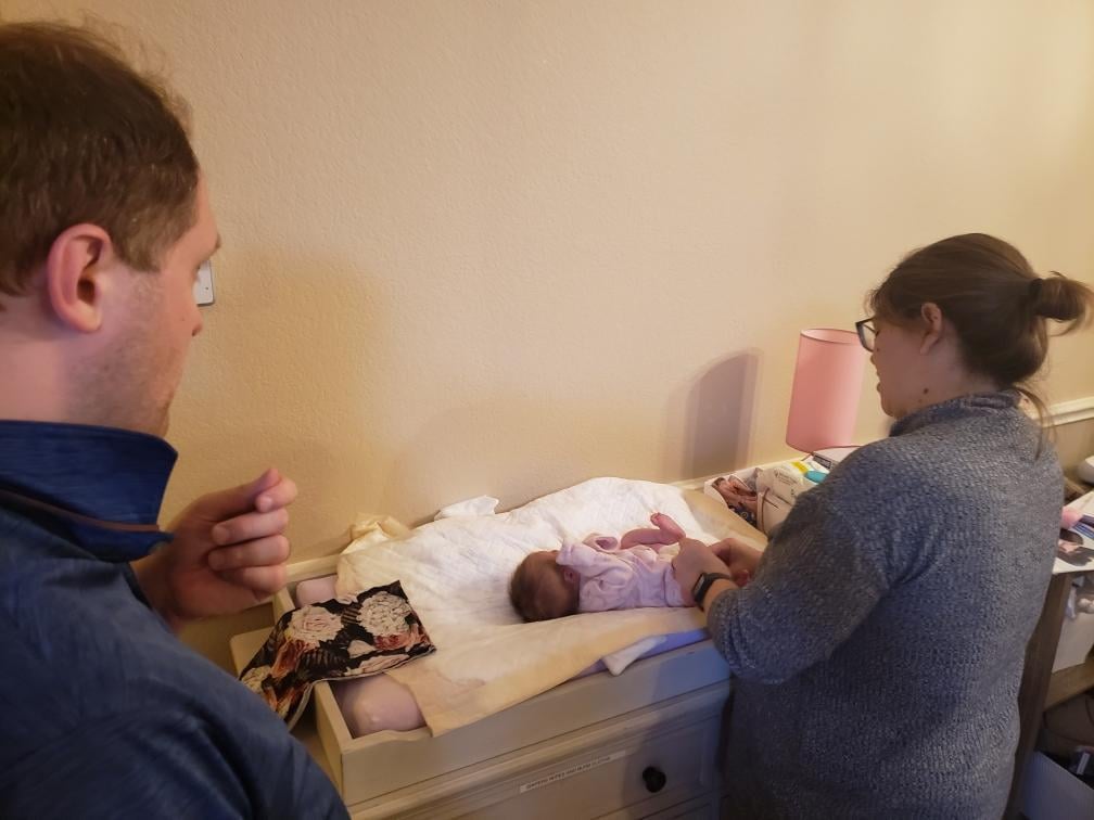 Doula Melanie Powell showing a new father how to change a diaper in their Mansifield Texas home