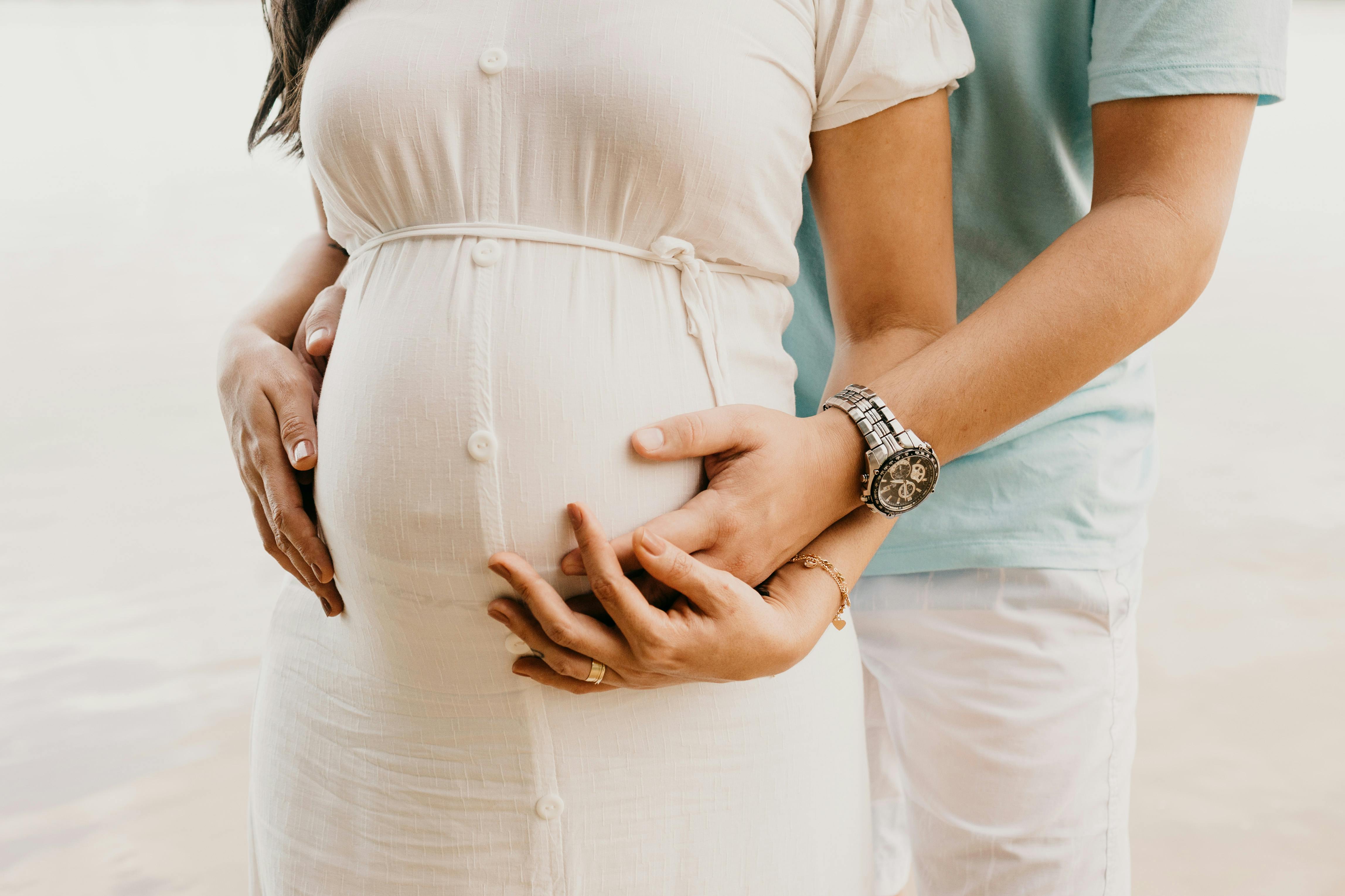 pregnant mom with her partner standing behind her holding her hand